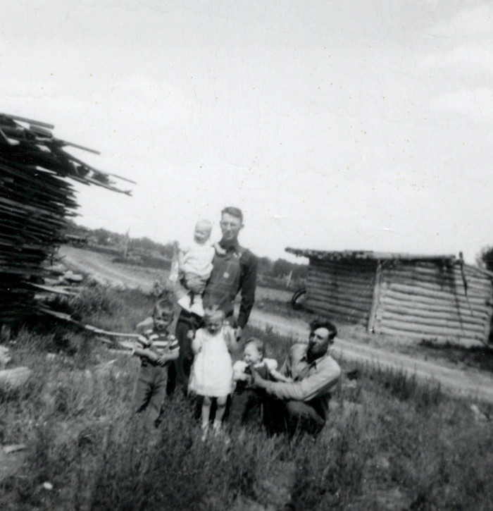 George standing, Elmer sitting with their children at the river place (Gring's)